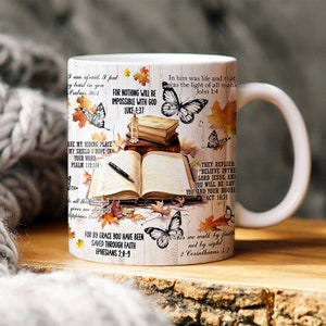 May include: White ceramic mug with a colorful design featuring butterflies, leaves, and bible verses. The text includes quotes such as "For nothing will be impossible with God" and "In him was life and that was the light of all mankind".