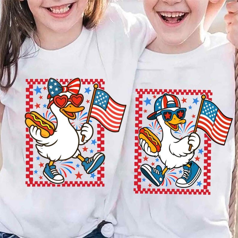 May include: Two white t-shirts with a cartoon duck wearing sunglasses and a red, white, and blue hat holding a hot dog and an American flag. The duck is surrounded by red, white, and blue fireworks. The text "USA" is on the shirt.