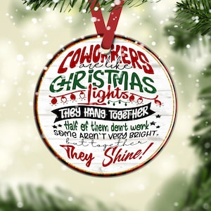 May include: Round white Christmas ornament with red and green text that reads "Coworkers are like Christmas lights. They hang together. Half of them don't work. Some aren't very bright, but together they shine!"