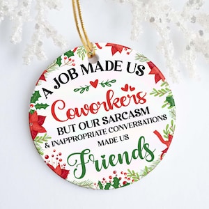 May include: A white round Christmas bauble with a red and green floral design. The bauble has the text "A job made us coworkers but our sarcasm & inappropriate conversations made us friends".