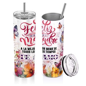 May include: A white stainless steel tumbler with a floral design and butterflies. The tumbler has a pink and purple inscription that reads "Feliz Dia de la Madre" and "A la mejor mama de todos los tiempos" with a heart. The tumbler comes with a lid and a straw.