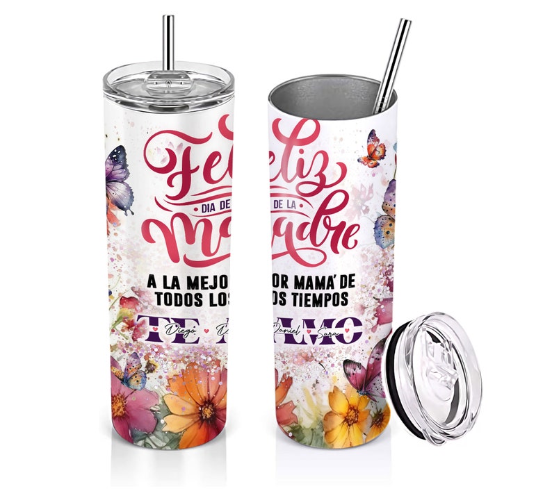 May include: A white stainless steel tumbler with a floral design and butterflies. The tumbler has a pink and purple inscription that reads "Feliz Dia de la Madre" and "A la mejor mama de todos los tiempos" with a heart. The tumbler comes with a lid and a straw.