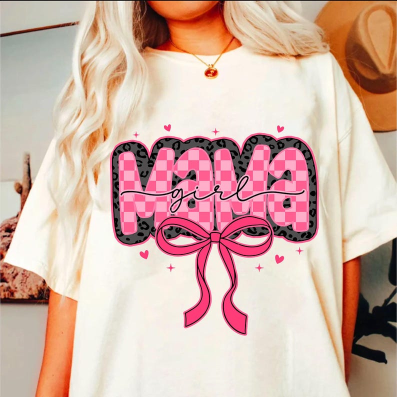 May include: White t-shirt with a pink and black graphic that says "Mama girl" with a pink bow.