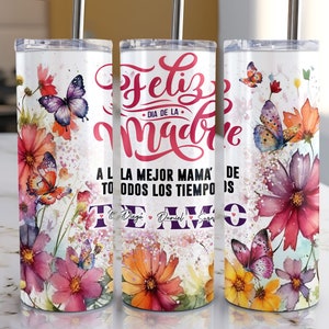 May include: A white tumbler with a floral design and butterflies. The tumbler has the text "Feliz Dia de la Madre" and "A la mejor mama' de todos los tiempos" in pink and red lettering. The tumbler also has the names "Diego", "Daniel", and "Sara" in purple lettering.