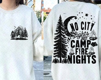 May include: White sweatshirt with a black graphic print of a mountain scene with a tent and trees on the front and the text "NO CITY lights JUST CAMP FIRE NIGHTS" with a moon, stars, and trees on the back.