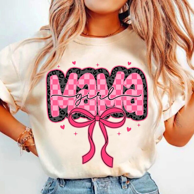 May include: White t-shirt with a pink and black graphic that says "Mama girl" with a pink bow.