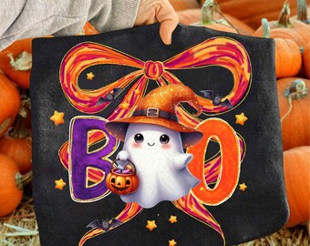 May include: Black Halloween tote bag with a cartoon ghost wearing a witch hat and holding a pumpkin bucket. The word "BOO" is displayed in orange and purple letters. A large orange and red bow is at the top of the bag, with bats and stars.