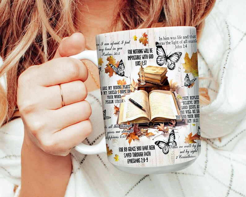 May include: White ceramic mug with a colorful design featuring butterflies, leaves, and bible verses. The mug has a handle and is filled with a brown liquid. The text on the mug includes verses from the Bible, such as "For nothing will be impossible with God" and "In him was life and that was the light of all mankind."