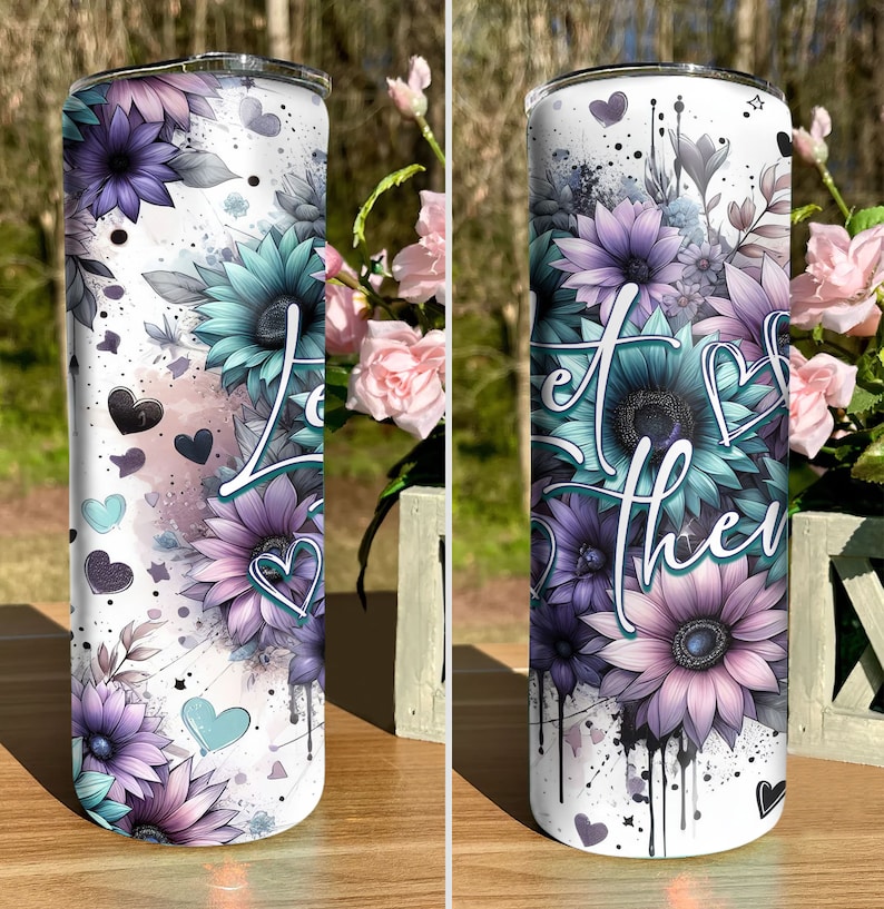 May include: A white stainless steel tumbler with a floral design featuring purple, blue, and pink flowers. The tumbler has a white background with black splatters of paint. The text "Let the" is visible on the tumbler.