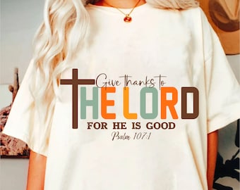 Peut inclure: T-shirt blanc avec un graphisme coloré qui dit "Give Thanks to The Lord For He Is Good Psalm 107:1".