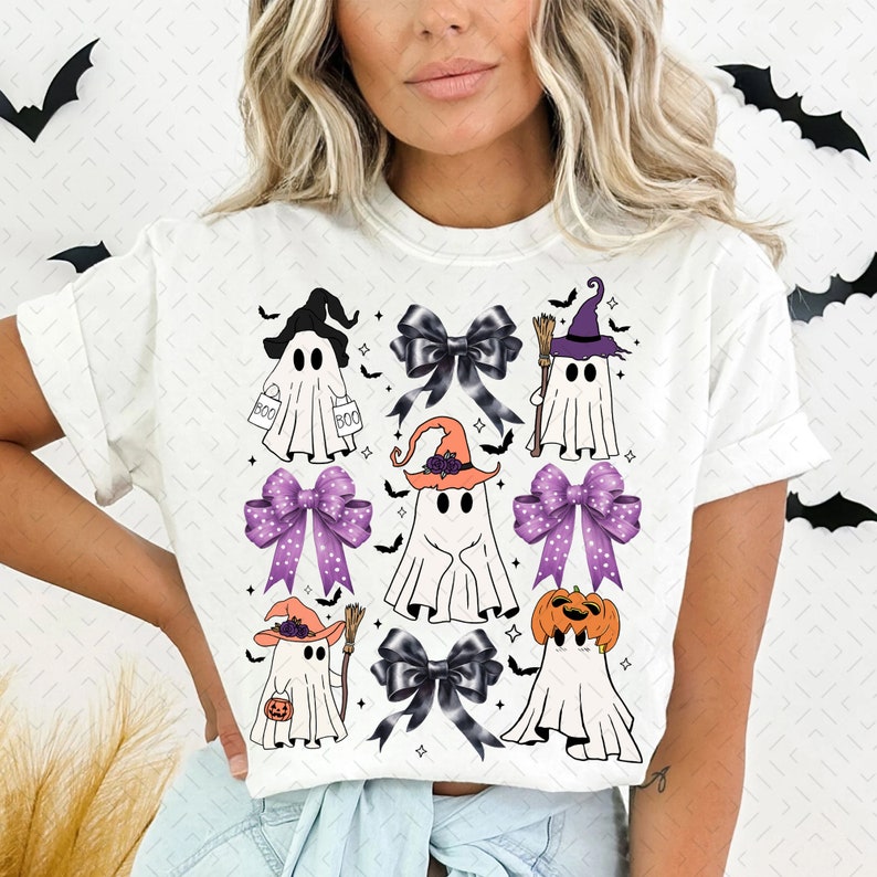 Puede incluir: Camiseta blanca con tem&aacute;tica de Halloween con m&uacute;ltiples im&aacute;genes de fantasmas con sombreros de bruja y sosteniendo calabazas y cubos de dulces. Los fantasmas est&aacute;n rodeados de lazos morados y negros.