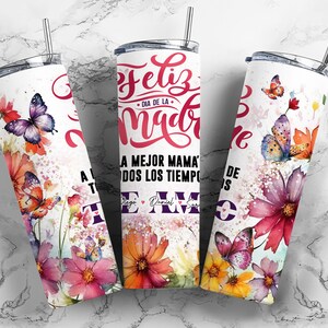 May include: A white stainless steel tumbler with a watercolor design of butterflies and flowers. The text "Feliz Dia de la Madre" and "A la mejor mama de todos los tiempos te amo" is printed on the tumbler.