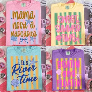 May include: Four colorful t-shirts with summer-themed graphics. The shirts are pink, yellow, blue, and purple. Each shirt has a different phrase: "Mama Need a Margarita," "Sweet Summer Time," "It's River Time," and "Boatin' and Floatin'."