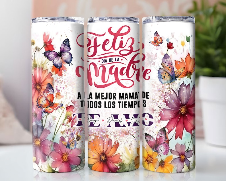 May include: White stainless steel tumbler with a floral design featuring butterflies and the text "Feliz Dia de la Madre A la Mejor Mama de Todos los Tiempos Te Amo Diego Daniel Sara".