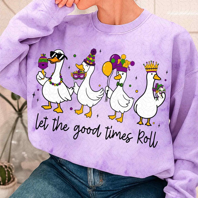 May include: A purple tie-dye sweatshirt featuring four cartoon geese in festive attire. Each goose is holding a Mardi Gras item, such as a maraca, mask, or balloons. The text "Let the good times Roll" is printed below the geese.