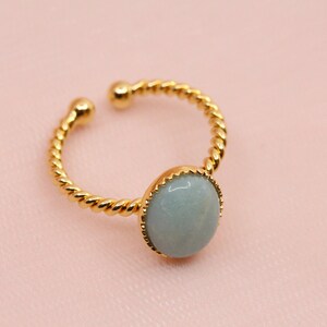 May include: A gold ring with a twisted band and a light blue round gemstone.