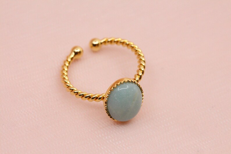 May include: A gold ring with a twisted band and a light blue round gemstone.