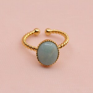 May include: A gold ring with a twisted band and a light blue oval gemstone.