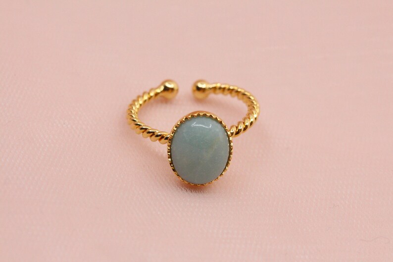 May include: A gold ring with a twisted band and a light blue oval gemstone.