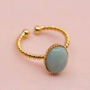 May include: A gold ring with a twisted band and a light blue oval gemstone.