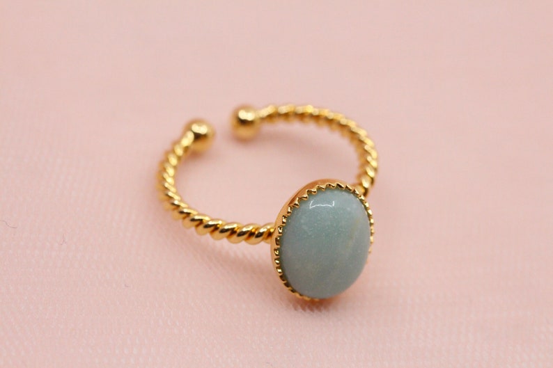 May include: A gold ring with a twisted band and a light blue oval gemstone.