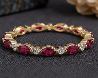 May include: A gold eternity band featuring an alternating pattern of marquise-cut red rubies and round-cut white diamonds. The ring is crafted with a polished gold setting that secures each gemstone in a continuous, circular arrangement.