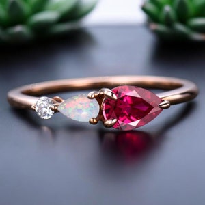 Puede incluir: Un anillo de oro rosa con una piedra preciosa de rubí en forma de pera, una piedra preciosa de ópalo en forma de pera y un pequeño diamante redondo.