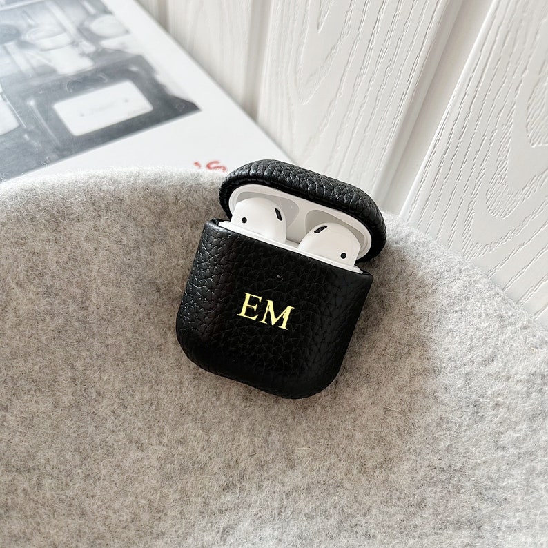 May include: Black leather Airpods case with the initials "EM" embossed in gold.