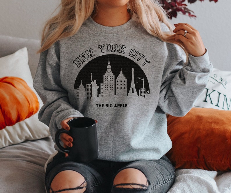 May include: A gray sweatshirt with a black graphic of the New York City skyline and the text "New York City" and "The Big Apple".