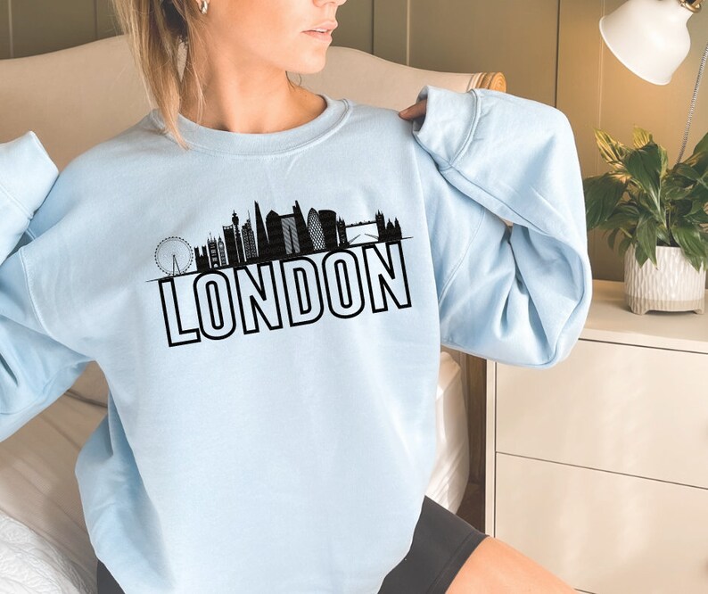 May include: A light blue sweatshirt with a black silhouette of the London skyline and the word "LONDON" in bold black letters.