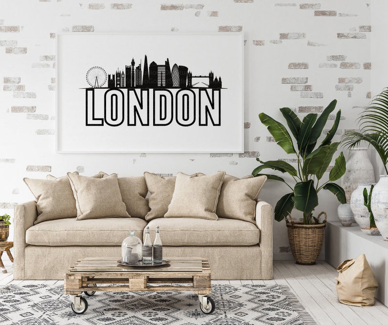 May include: A black and white illustration of the London skyline with the word "LONDON" in bold letters below. The illustration is framed and hanging on a white brick wall above a beige sofa.