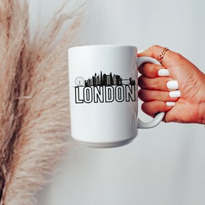 May include: White ceramic mug with a black silhouette of the London skyline and the word "LONDON" printed in black.