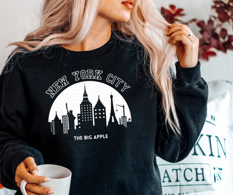 May include: Black sweatshirt with a white graphic of the New York City skyline and the text "New York City" and "The Big Apple".