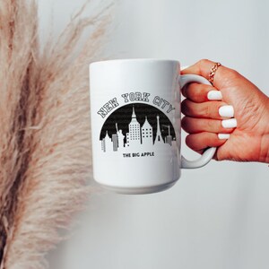 May include: White ceramic mug with a black graphic of the New York City skyline and the text "NEW YORK CITY THE BIG APPLE".