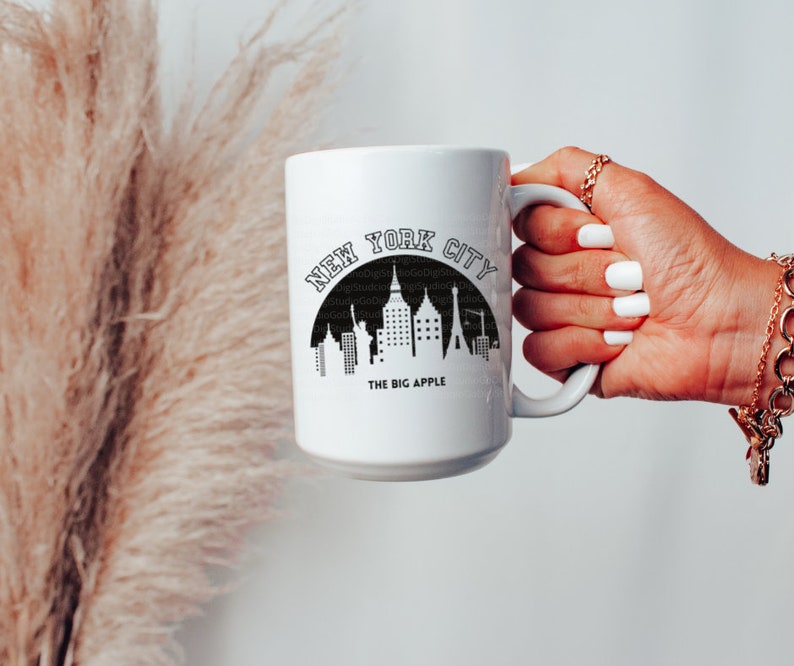 May include: White ceramic mug with a black graphic of the New York City skyline and the text "NEW YORK CITY THE BIG APPLE".