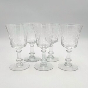 Peut inclure: Ensemble de cinq verres à vin en verre transparent avec un motif gravé délicat. Les verres ont un pied et un large bol.