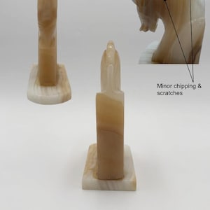 May include: Two onyx sculptures, one a tall, rectangular shape and the other a horse head. The sculptures are beige and cream-colored with natural veining. The horse head has minor chipping and scratches. Both sculptures are on a rectangular base.