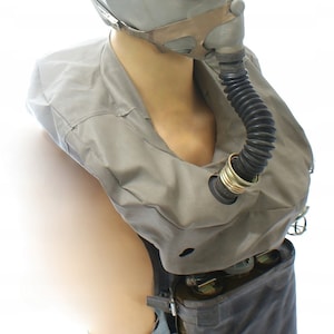 Op de afbeelding: Een grijs gasmasker met een zwarte slang en een grijze canvas tas met een zwarte band en een zwarte canister. Het gasmasker heeft een helder vizier en een zwart rubberen mondstuk.