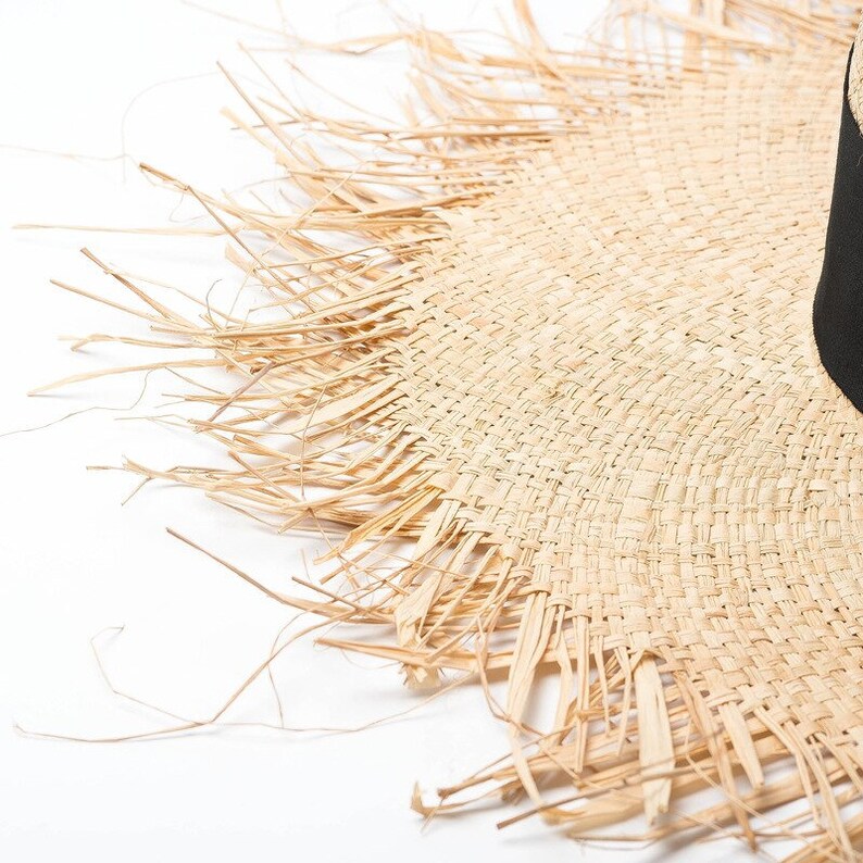May include: Close-up of a straw hat with a frayed edge. The hat is made of woven straw and has a natural color.