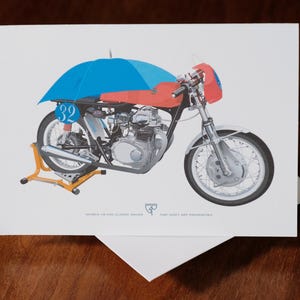 Op de afbeelding: Wenskaart met een vintage motorfiets illustratie. De motorfiets is rood en zwart met een blauwe parapluvormige afdekking. Het nummer 32 staat op de zijkant. De kaart staat op een witte achtergrond.