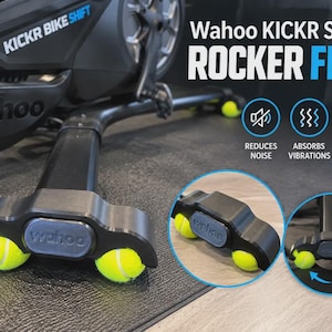 May include: Black Wahoo KICKR SHIFT rocker feet featuring two bright yellow tennis balls integrated into the base. The text reads Wahoo KICKR SHIFT ROCKER FEET, REDUCES NOISE, ABSORBS VIBRATIONS, and FLOOR FRIENDLY. The design allows for side-to-side motion.