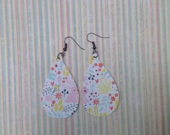 May include: A pair of teardrop-shaped earrings with a floral and bunny print. The earrings are white with pink, yellow, and blue accents.
