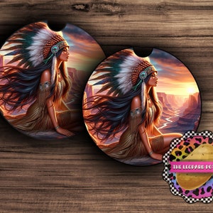 Puede incluir: Dos posavasos redondos para coche con una mujer nativa americana que lleva un tocado y ropa tradicional. La mujer está representada en un paisaje desértico con una puesta de sol de fondo. Los posavasos son negros con un acabado brillante.