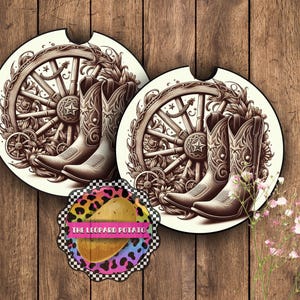 May include: Two white ceramic coasters with a brown and white design of cowboy boots and a wagon wheel. The design is surrounded by floral details.