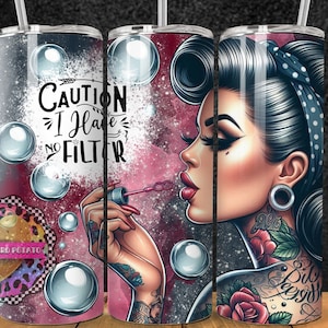 May include: A pink and black tumbler featuring a graphic of a woman blowing bubbles. The woman has a tattoo and a pin-up style hairdo. The text on the tumbler reads "Caution I Have No Filter".