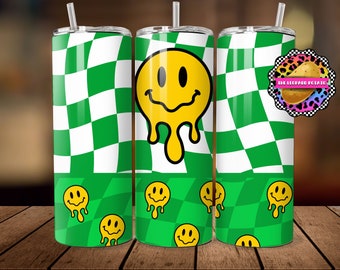 May include: A set of three stainless steel tumblers with a green and white checkered pattern. Each tumbler features a yellow melting smiley face design. The bottom section of the tumblers has smaller smiley faces on a green checkered background.