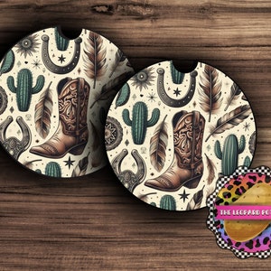 May include: Two round, cream-colored coasters with a black border. The coasters feature a repeating pattern of brown cowboy boots, green cacti, black horseshoes, and brown feathers. The coasters are perfect for protecting surfaces from condensation.