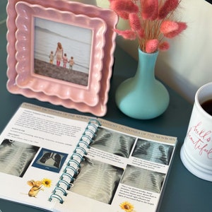 May include: An open book with a teal spiral binding. The book is titled "Transient Tachypnea of the Newborn". The pages contain black and white x-ray images of a baby's lungs. The book is open to a page with a sunflower and a mouse illustration.