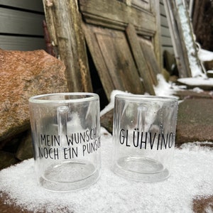 Könnte beinhalten: Zwei durchsichtige Glasbecher mit schwarzem Text. Der Becher links sagt "Mein Wunsch noch ein Punsch". Der Becher rechts sagt "Glühvino".