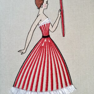 May include: Embroidered design of a woman in a red and white striped dress holding a red paintbrush. The dress has a white ruffle trim.